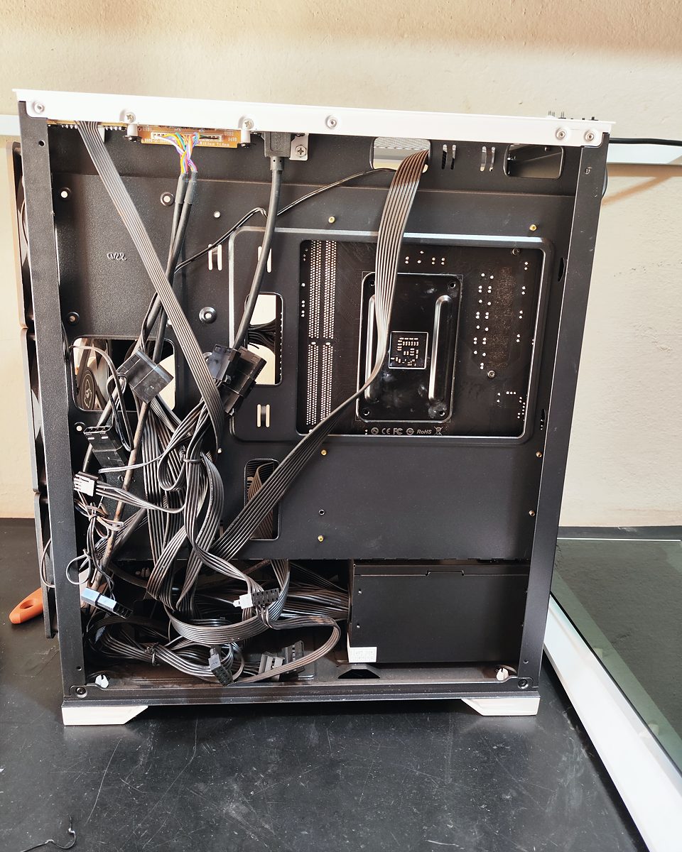 Parte de trás de um PC gamer com cabos soltos e desorganizados, antes da organização